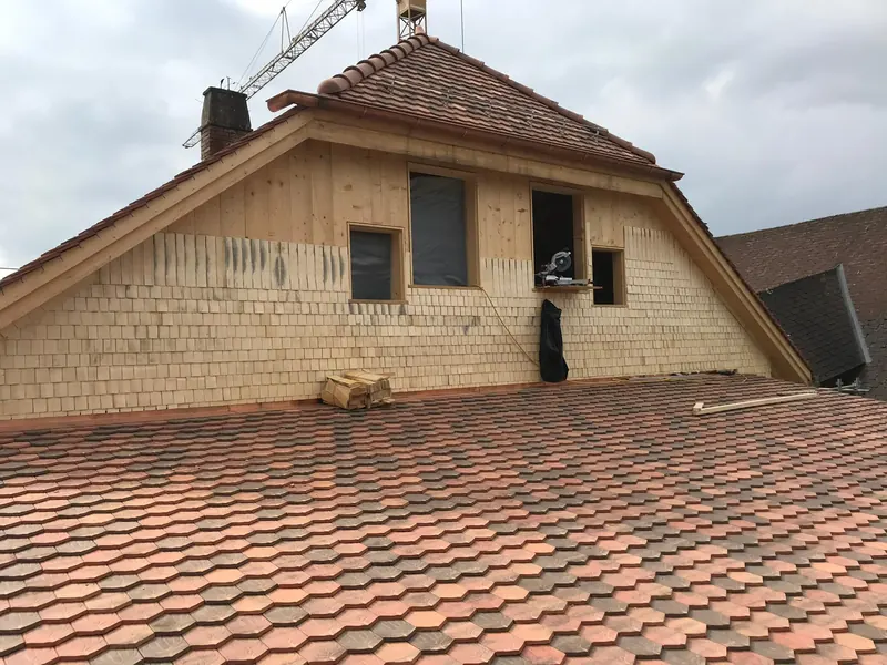Giebel eines Wohnhauses mit neuer, heller Holzschindelfassade
